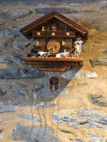 une horloge sur le côté d'un mur de pierre dans l'établissement Chalet Premium 10min Funiculaire Les Arcs, à Les Chapelles