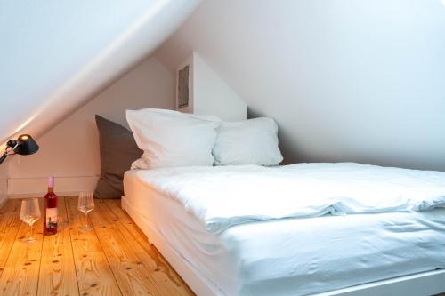 Cama blanca con botella de vino y lámpara en Altstadtliebesnest, en Constanza