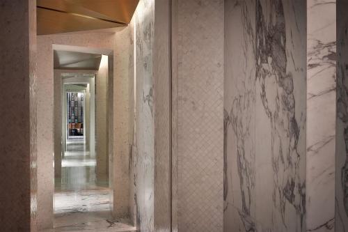 a hallway with marble walls and a hallway with a mirror at W Muscat in Muscat