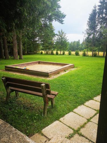 a park bench sitting in the grass next to a pool at Cabin near forest in Mlynčeky
