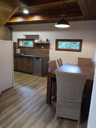 a kitchen with a wooden table with chairs and a refrigerator at Cabin near forest in Mlynčeky