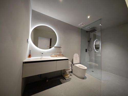 a bathroom with a sink and a toilet and a mirror at Qingcheng Mount SuXi Qingshan Forest Hotel in Chongzhou