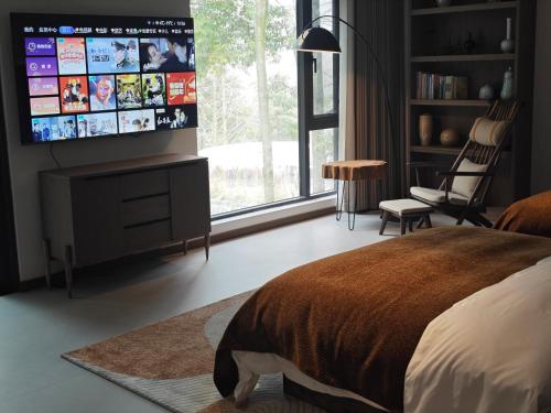 a bedroom with a flat screen tv on the wall at Qingcheng Mount SuXi Qingshan Forest Hotel in Chongzhou
