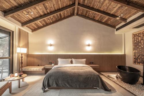 a bedroom with a large bed and a bath tub at Qingcheng Mount SuXi Qingshan Forest Hotel in Chongzhou