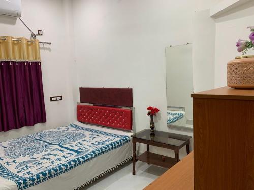 a bedroom with a bed and a table and a mirror at Kolkata Sarkar Villa Homestay in Kolkata
