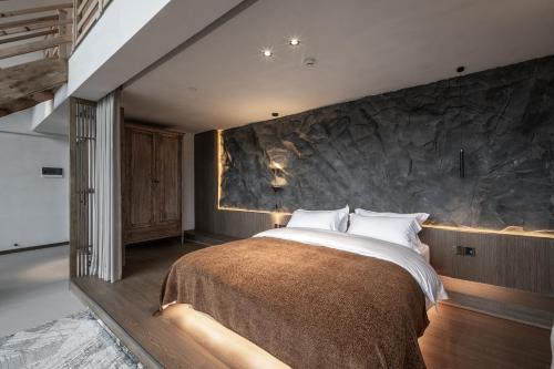 a bedroom with a large bed with a stone wall at Qingcheng Mount SuXi Qingshan Forest Hotel in Chongzhou