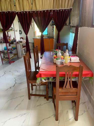 a dining room table with a red table cloth and chairs at Kolkata Sarkar Villa Homestay in Kolkata
