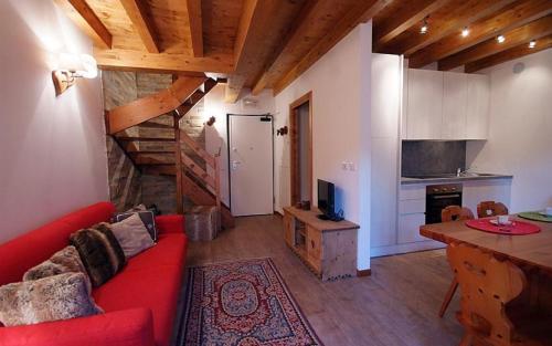 a living room with a red couch and a kitchen at Villaggio delle Alpi in Pré-Saint-Didier