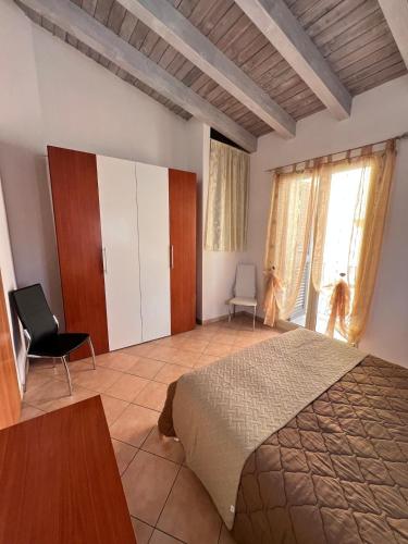 a bedroom with a large bed and a chair at Casa Vacanze A' Lanterna in Licata
