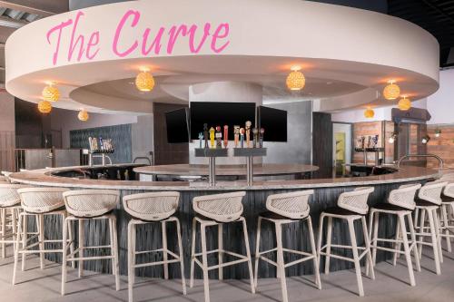 a bar in a restaurant with stools around it at Sheraton Mesa Hotel at Wrigleyville West in Mesa