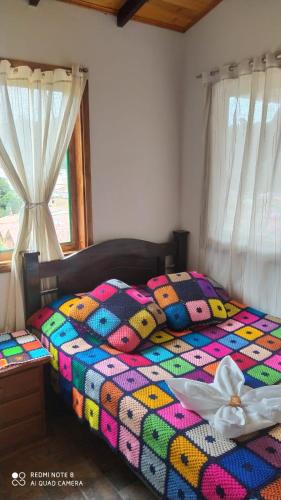 a bed with a colorful quilt in a bedroom at HOSPEDAJE LA LOMITA, Cabañas in Monguí