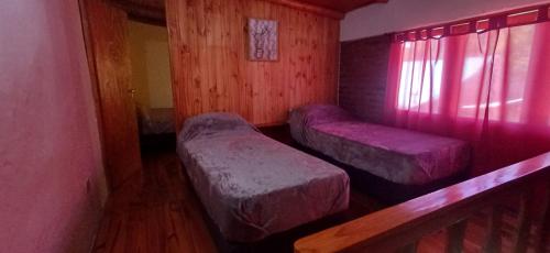 a room with two beds and a window with pink lights at Alojamiento Rivadavia in El Bolsón