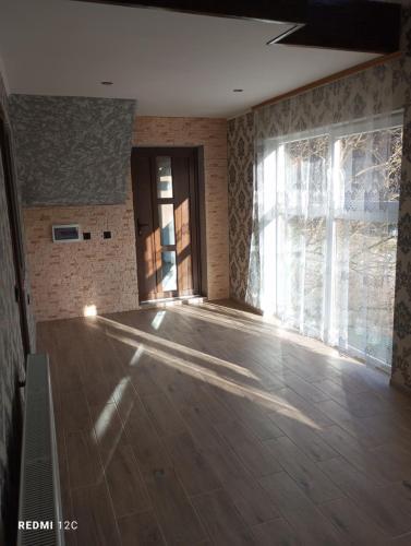 an empty room with a wooden floor and a large window at Біля Річки in Kvasy