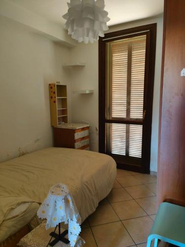 a bedroom with a bed and a window and a chandelier at Bilocale Garzella 1 in Cascina