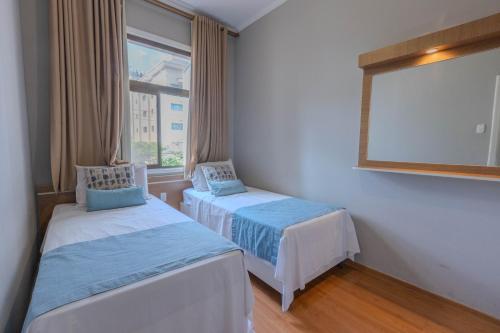 a room with two beds and a large window at Hotel Minas Gerais in Poços de Caldas