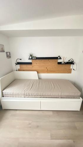 - un lit blanc dans une chambre dotée d'un mur blanc dans l'établissement Studio plein de charme, à Les Sables-dʼOlonne