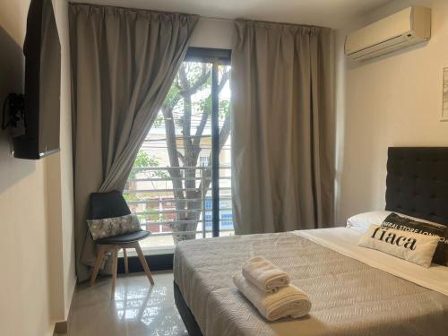 Schlafzimmer mit einem Bett und einem Fenster mit einem Stuhl in der Unterkunft Estudio 12 - Mural Home in Santiago del Estero