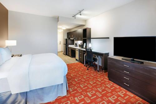 a hotel room with a bed and a flat screen tv at TownePlace Suites Dallas Plano/Richardson in Plano