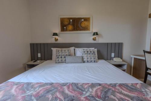 a bedroom with a large bed and two tables at Hotel Minas Gerais in Poços de Caldas