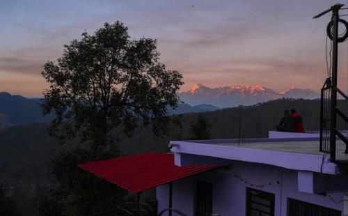 two people sitting on the roof of a building watching the sunset at Saanjh Binsar, Himalaya ka Dwaar in Hawālbāgh