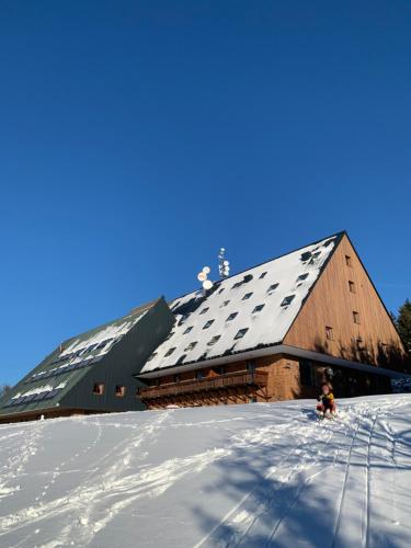 a large wooden barn with snow on the roof at Apartmán Žalý in Benecko