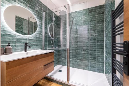 La salle de bains est pourvue de carrelage vert, d'un lavabo et d'une douche. dans l'établissement Ambiance nature aux portes des Halles de Nîmes, à Nîmes