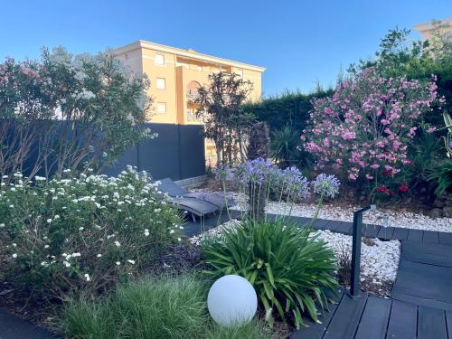 a garden with flowers and plants and a building at Les Enganes in Fréjus