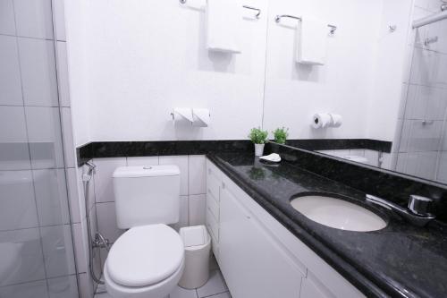 a white bathroom with a toilet and a sink at Verona Hplus Long Stay in Brasília