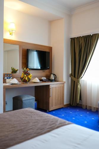a hotel room with a bed and a desk with a television at Palan Ski & Convention Resort Hotel in Erzurum