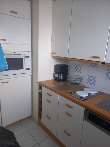 une cuisine avec des armoires blanches et un comptoir dans l'établissement Sea side apartment, à Banyuls-sur-Mer