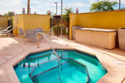 a swimming pool with chairs and a table at TownePlace Suites by Marriott Phoenix Goodyear in Goodyear