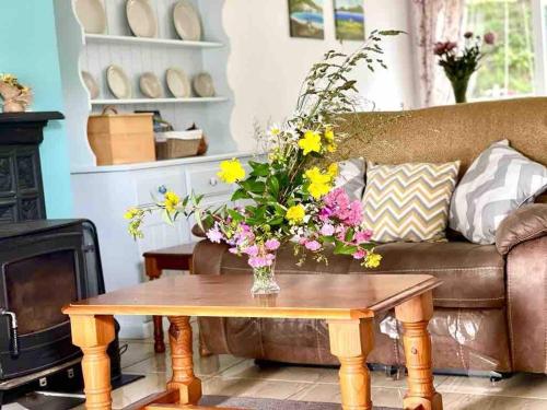 salon z kanapą i stołem z kwiatami w obiekcie Fionas thatched cottage eile w Killarney