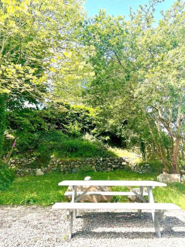 a white bench sitting on the gravel in a park at Fionas thatched cottage eile in Killarney