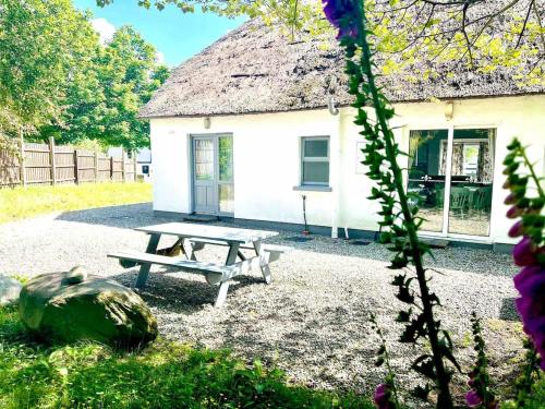 a picnic table in front of a white building at Fionas thatched cottage eile in Killarney
