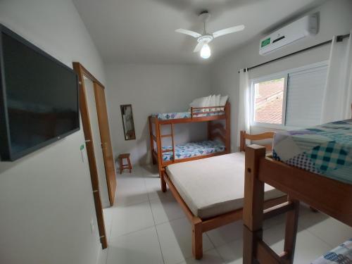 a bedroom with a bed and a flat screen tv at Canto Verde Aptos II in Caraguatatuba