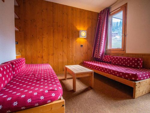 une chambre avec deux canapés rouges et une fenêtre dans l'établissement Studio pratique à Valmorel, pied des pistes, 4 couchages, proche remontées et commerces - FR-1-356-363, à Valmorel