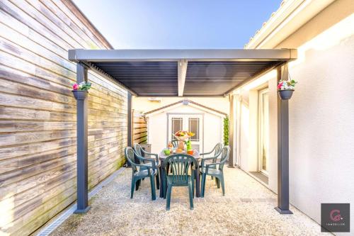 un patio avec une table et des chaises sous une pergola dans l'établissement Biscarrosse Bourg, jolie petite maison pour 4 personnes avec Terrasse et jardin, à Biscarrosse