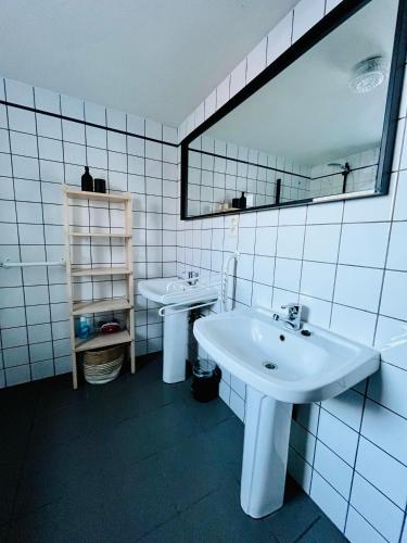 a white bathroom with two sinks and a mirror at Maison des M in Houffalize