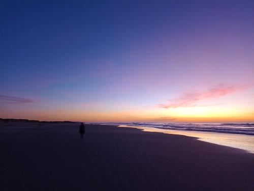 a person walking on the beach at sunset at Nalu in Passo De Torres