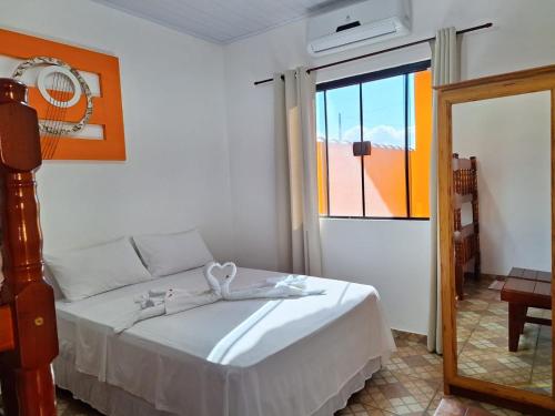 a bedroom with a white bed and a window at Hospedagem Familiar Yamane in Ilha Comprida
