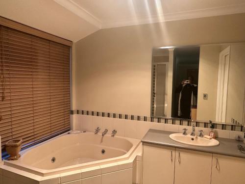 a bathroom with a tub and two sinks and a person taking a picture at Country Oasis on Evans Street in Collie