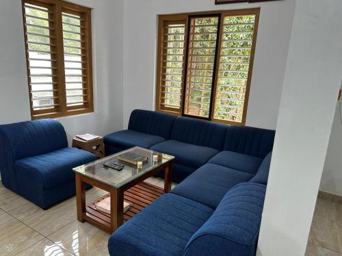 un soggiorno con divani blu e tavolino da caffè di Serenity Home Stay a Sultan Bathery