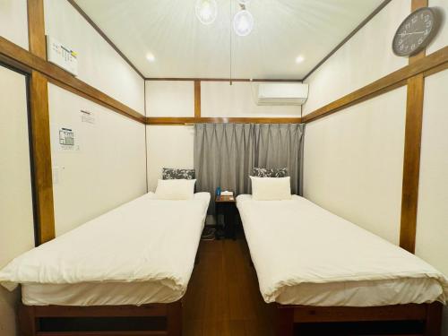 2 letti in una camera con orologio a parete di Oji House-KI0022 a Tokyo