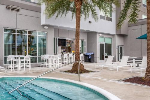 a swimming pool with chairs and a table and a building at TownePlace Suites By Marriott Orlando Southwest Near Universal in Orlando
