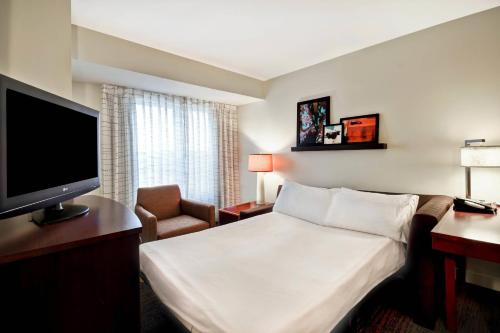 a hotel room with a bed and a flat screen tv at Residence Inn by Marriott Stillwater in Stillwater