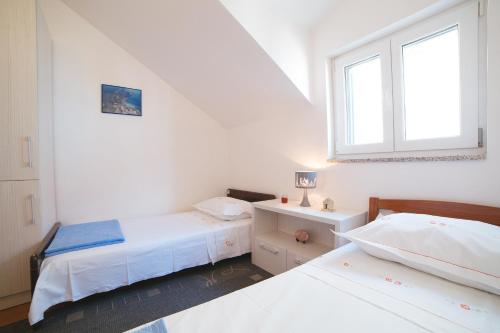 a white room with two beds and a window at Apartment Aldo in Omiš