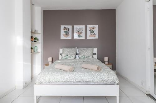 une chambre blanche avec un lit blanc avec deux oreillers dans l'établissement L 'Émeraude Toulousaine, à Toulouse