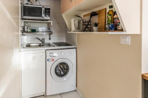 une cuisine avec un lave-linge et un micro-ondes dans l'établissement L 'Émeraude Toulousaine, à Toulouse