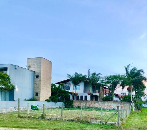 a building with palm trees behind a fence at Espaço para Motor Home ou Trailer in Garopaba