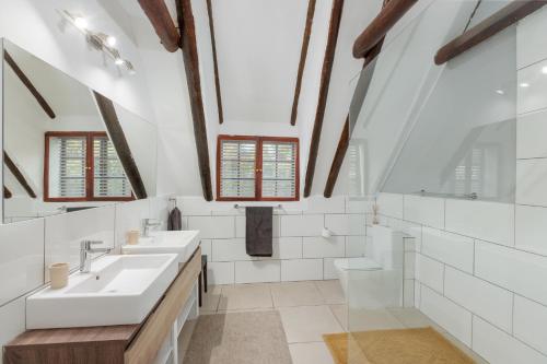 a bathroom with two sinks and two mirrors at Die Rietdak - Reetdachhaus mit vier Schlafzimmern in Cape Town